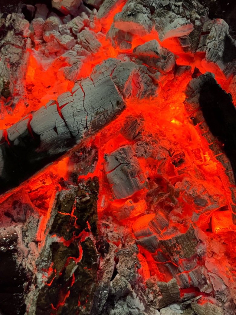 Brasas de leña al rojo vivo, cubiertas de ceniza blanca