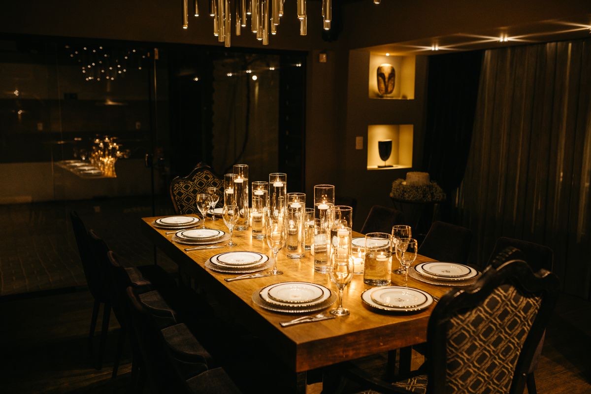 Mesa larga de madera preparada para la cena, con velas encendidas y luz cálida