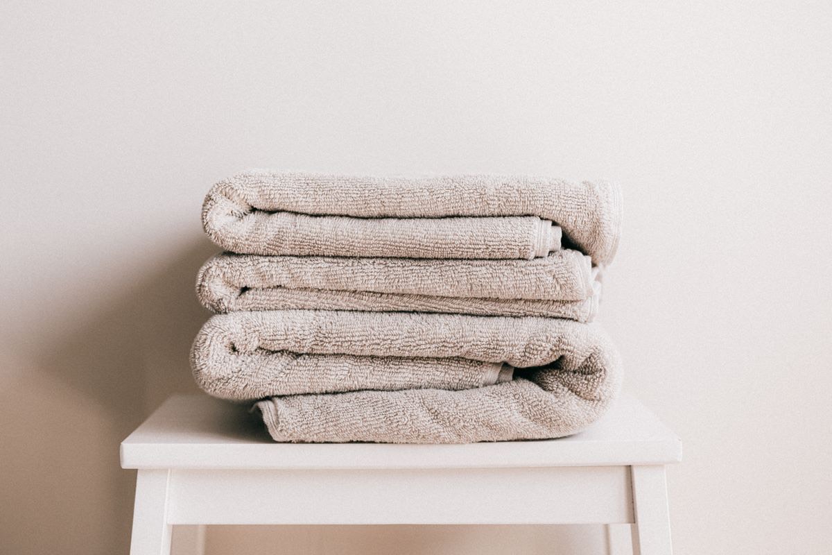 Toallas beige dobladas sobre un taburete blanco